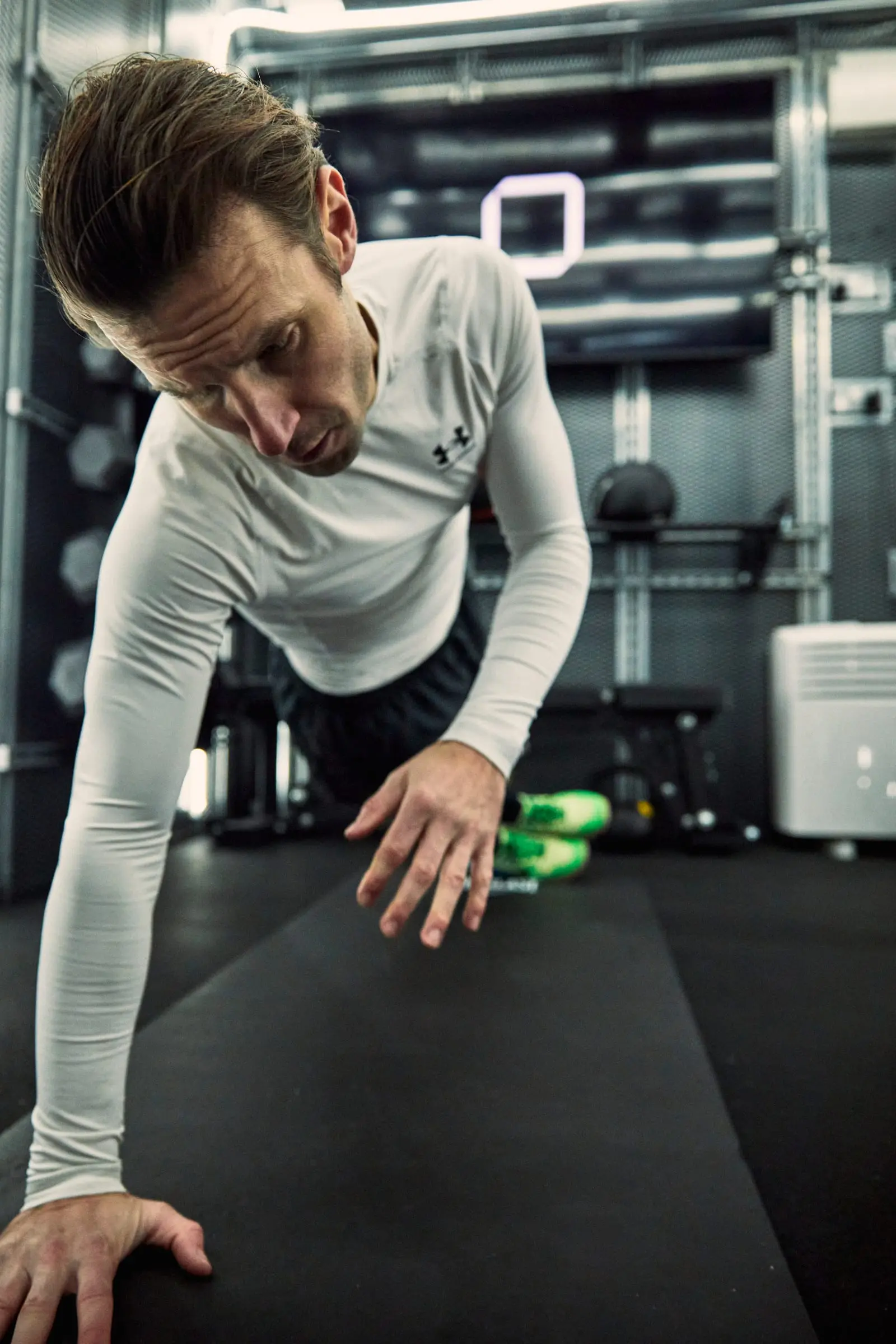 A man in a one-handed press-up position on a mat inside a PT Pod
